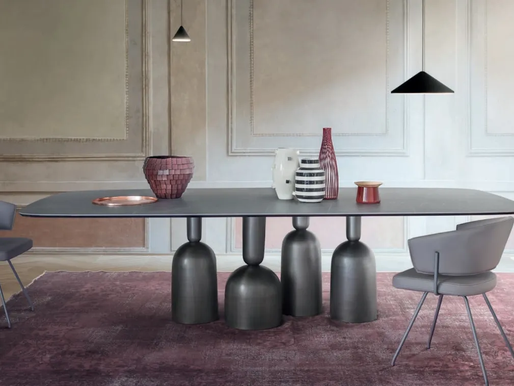 Tavolo Cop con piano in ceramica e base in metallo formata da elementi stilizzati ispirati a bottiglie, calici preziosi e coppe di champagne di Bonaldo